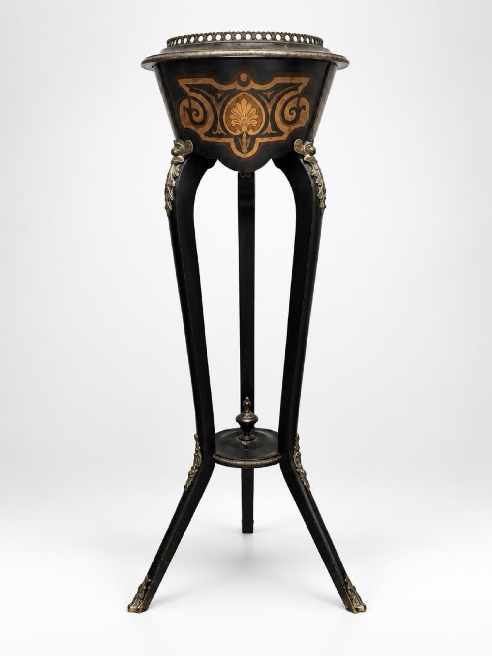 An ebonised Napoleon III tripod jardiniere stand featuring inlaid floral marquetry on a tapered basin, decorative brass mounts, cabriole legs, and a low central finial stretcher.