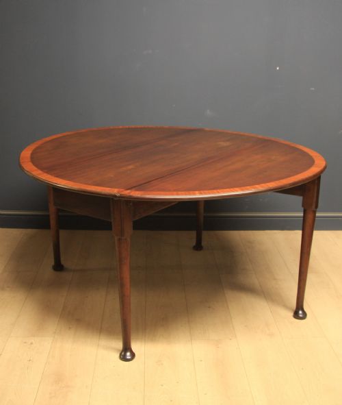 fig 1. A Georgian mahogany drop-leaf dining table featuring crossbanded inlay borders, tapered legs, and pad feet.