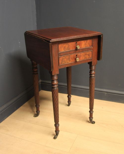 fig 1. A Regency mahogany drop-leaf table featuring two drawers with lighter wood fronts, round brass knobs, and spiral-turned legs terminating in brass castors.