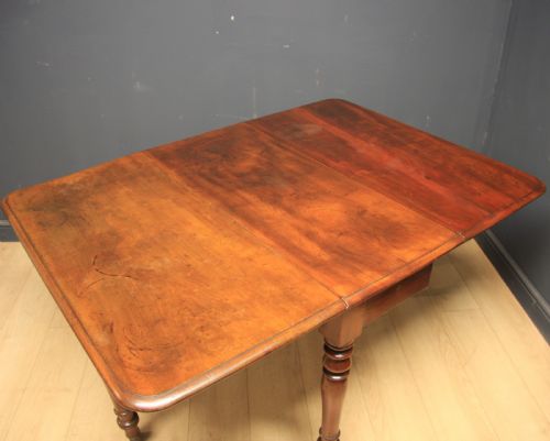 fig 1. A Victorian warm brown mahogany drop-leaf dining table featuring turned legs and brass castors.