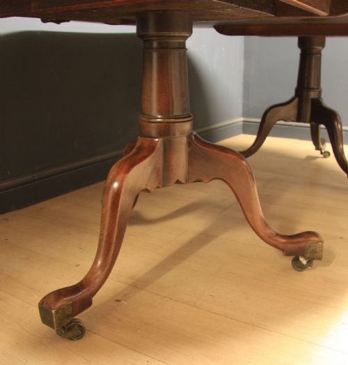 fig 1. A Georgian mahogany twin-pedestal extending dining table with rounded ends and brass castors on a light wooden floor.