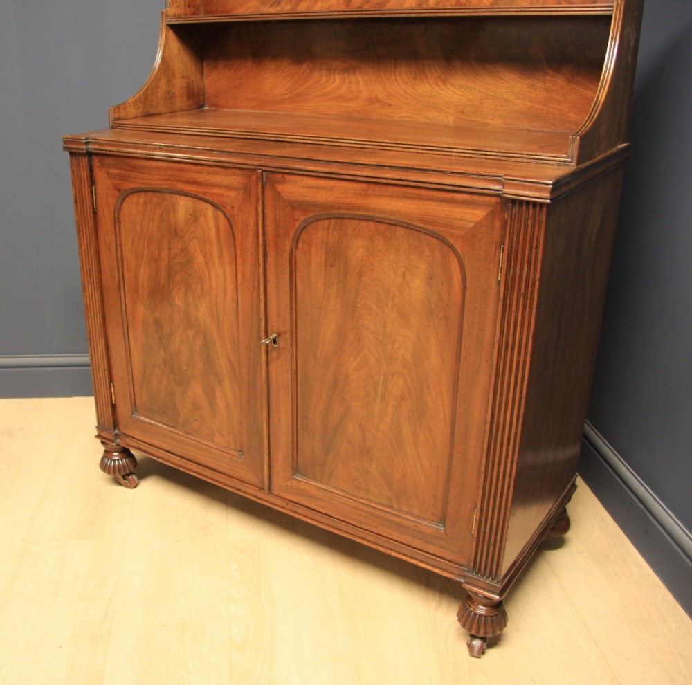 A William IV mahogany sideboard featuring a raised back shelf, flame mahogany panelled cupboard doors, reeded side pilasters, and carved turned feet. View III