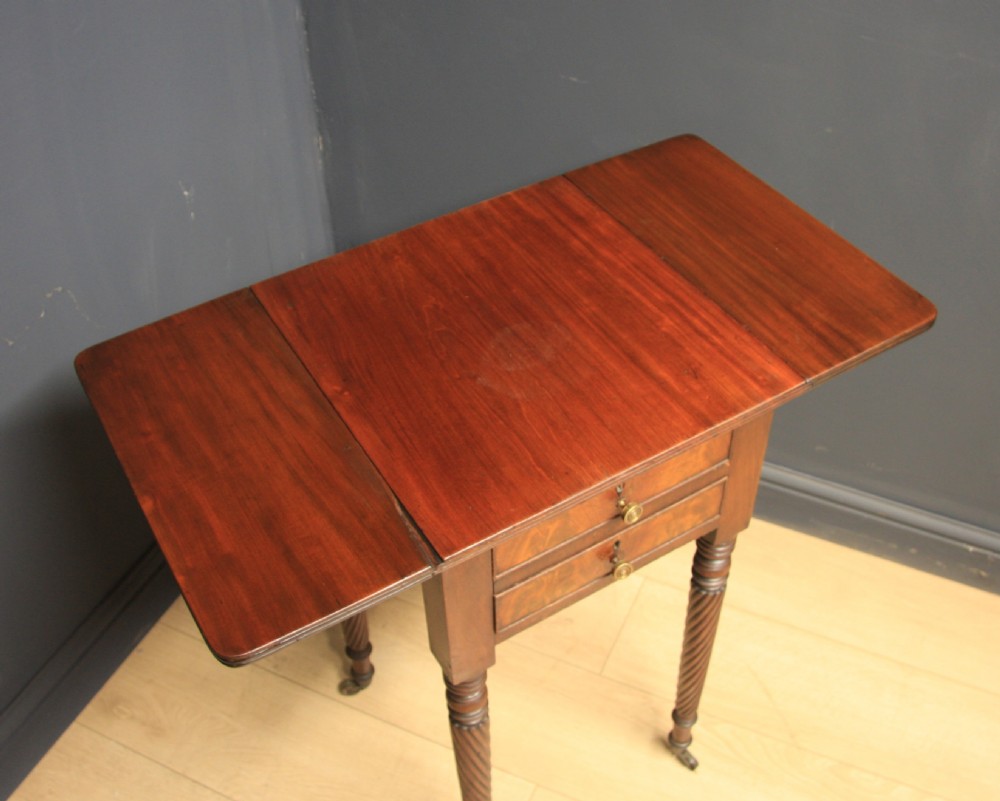 A Regency mahogany drop-leaf table featuring two drawers with lighter wood fronts, round brass knobs, and spiral-turned legs terminating in brass castors. View III