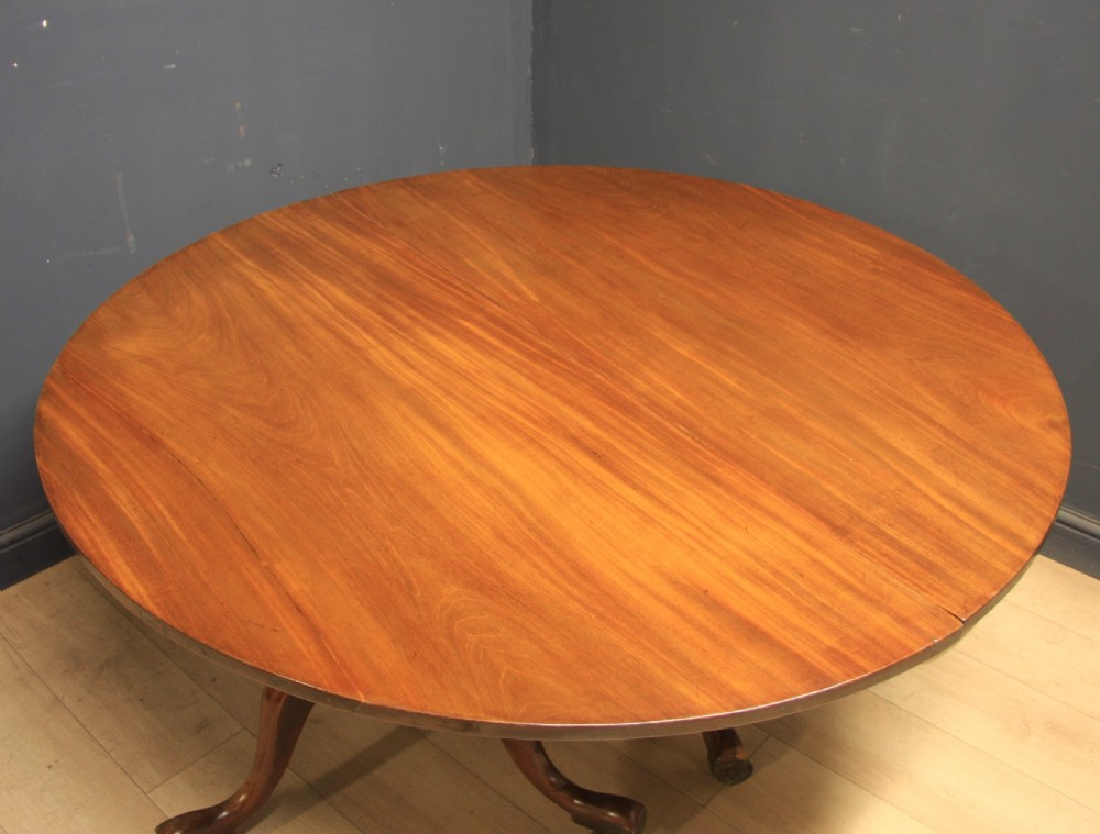 A Georgian mahogany twin-pedestal extending dining table with rounded ends and brass castors on a light wooden floor. View IV