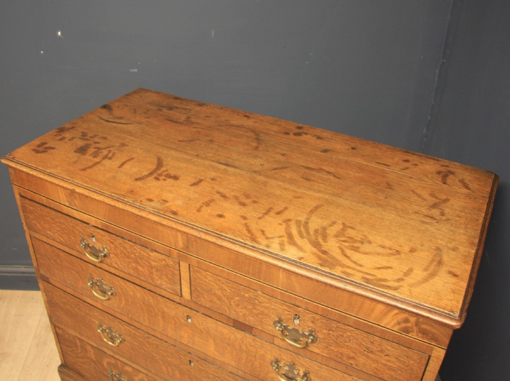 A Georgian oak chest of drawers featuring two short over three long drawers with brass swan-neck handles and bracket feet. View III