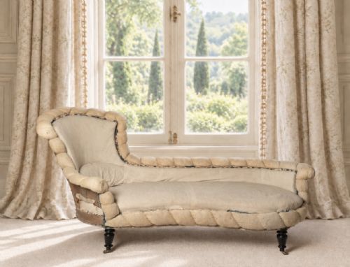 fig 1. A nineteenth-century French Napoleon III chaise longue upholstered in natural calico with rolled piecrust border trim and turned black ebonised legs on castors.
