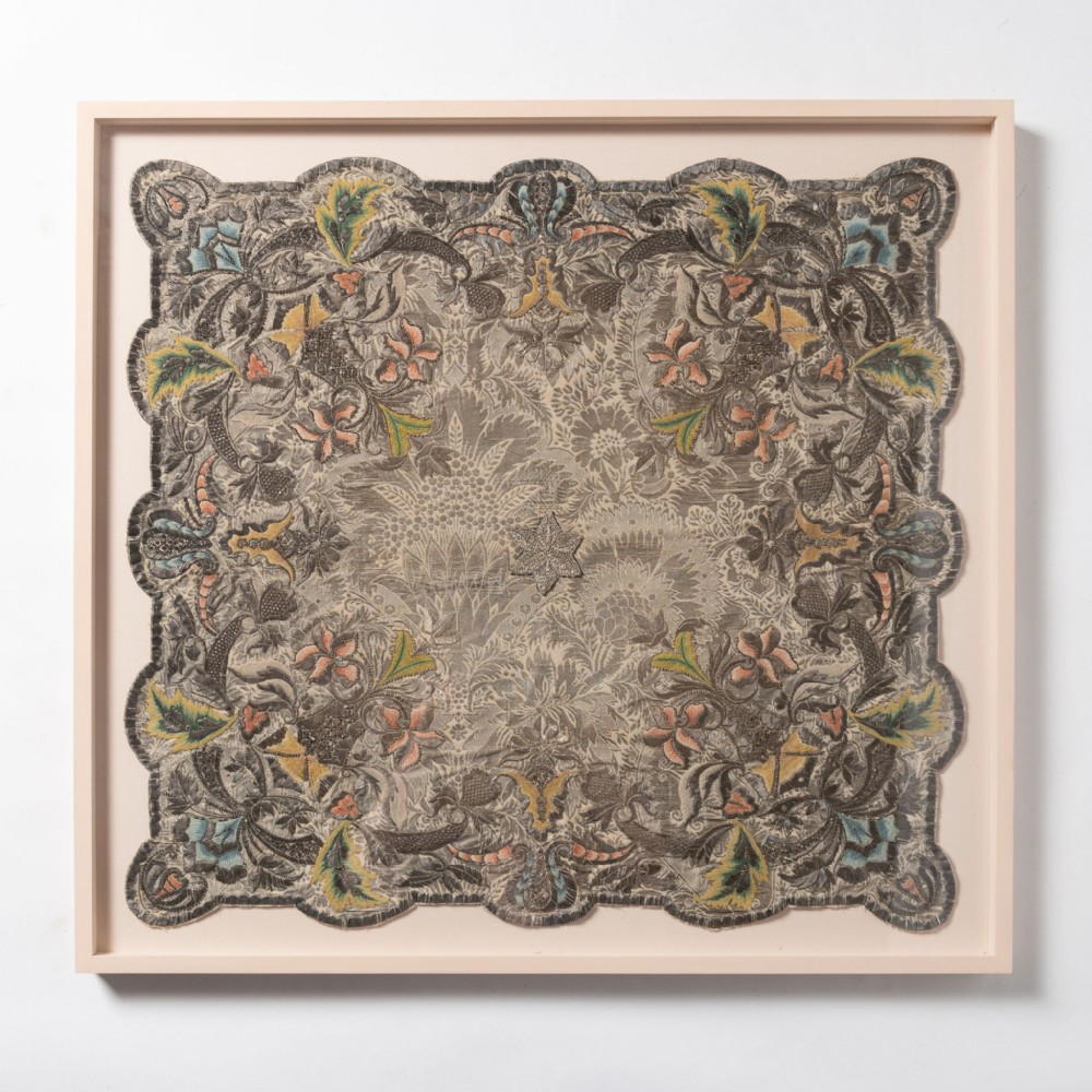 An 18th-century square embroidered silk panel with scalloped edges and detailed botanical motifs, presented inside a light timber frame.