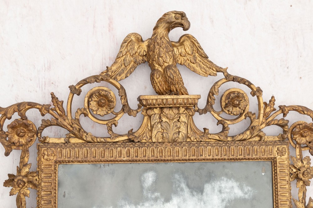 An 18th-century Italian giltwood wall mirror featuring a carved eagle crest, floral side accents, and a patinated two-part mirror plate. View III
