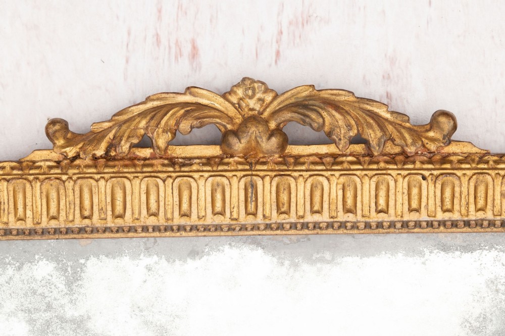 An 18th-century Italian giltwood wall mirror featuring a carved eagle crest, floral side accents, and a patinated two-part mirror plate. View VIII