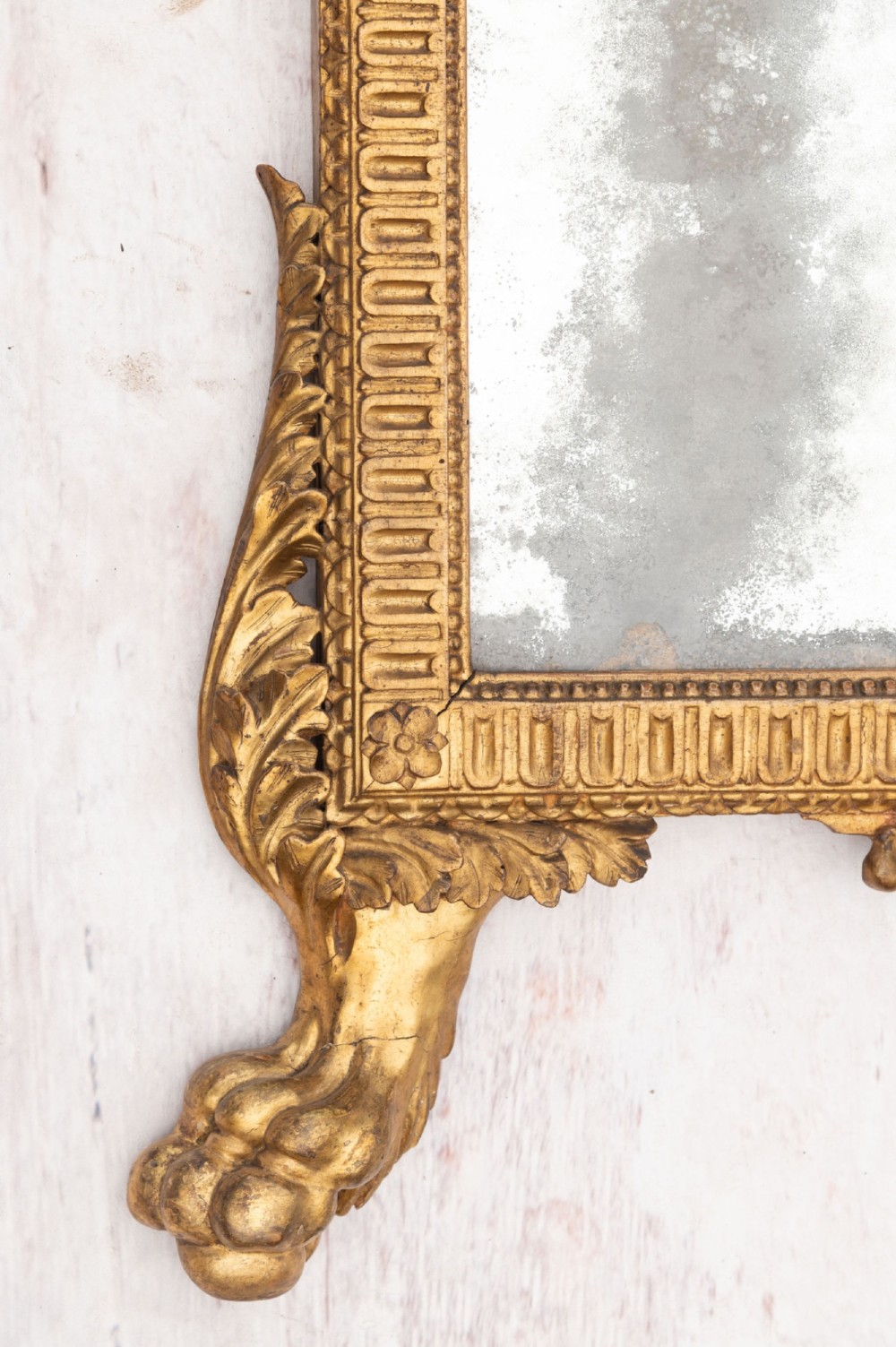 An 18th-century Italian giltwood wall mirror featuring a carved eagle crest, floral side accents, and a patinated two-part mirror plate. View IX