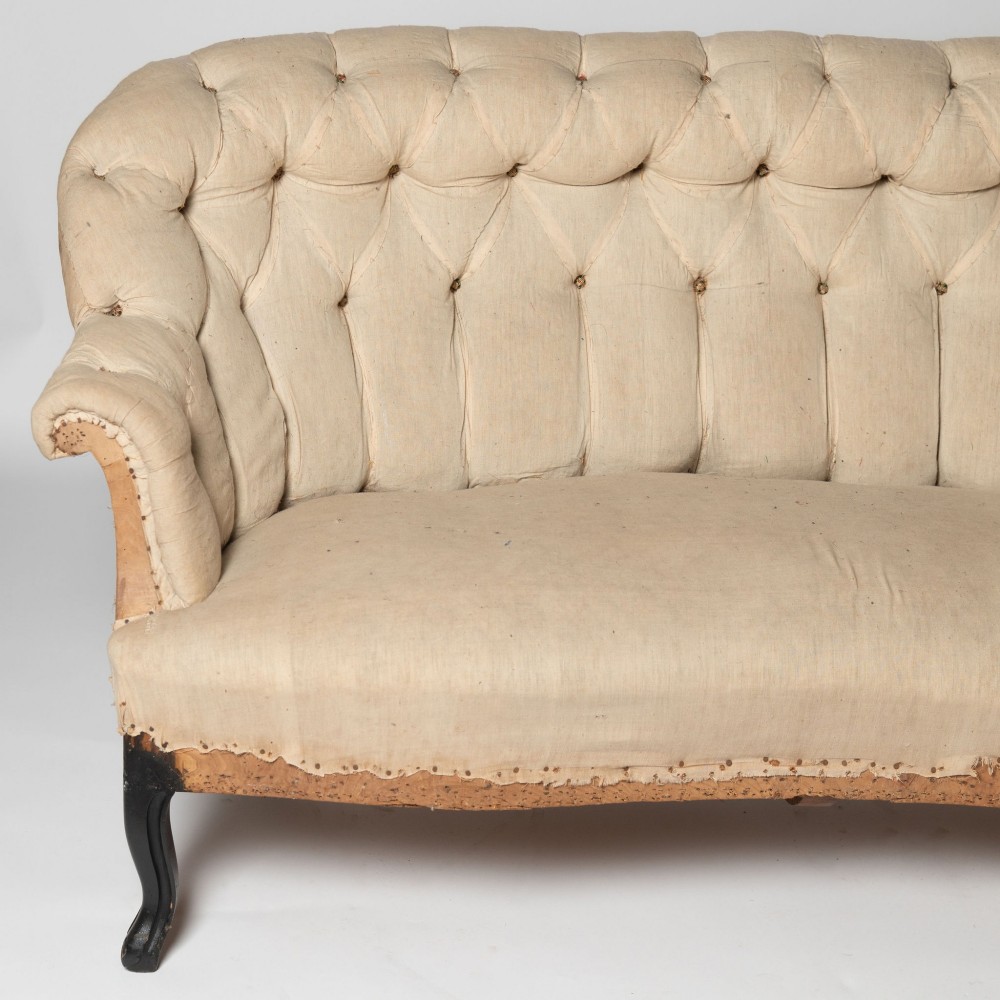 An antique French sofa upholstered in cream calico fabric with deep button tufting along the backrest and dark cabriole front legs. View II