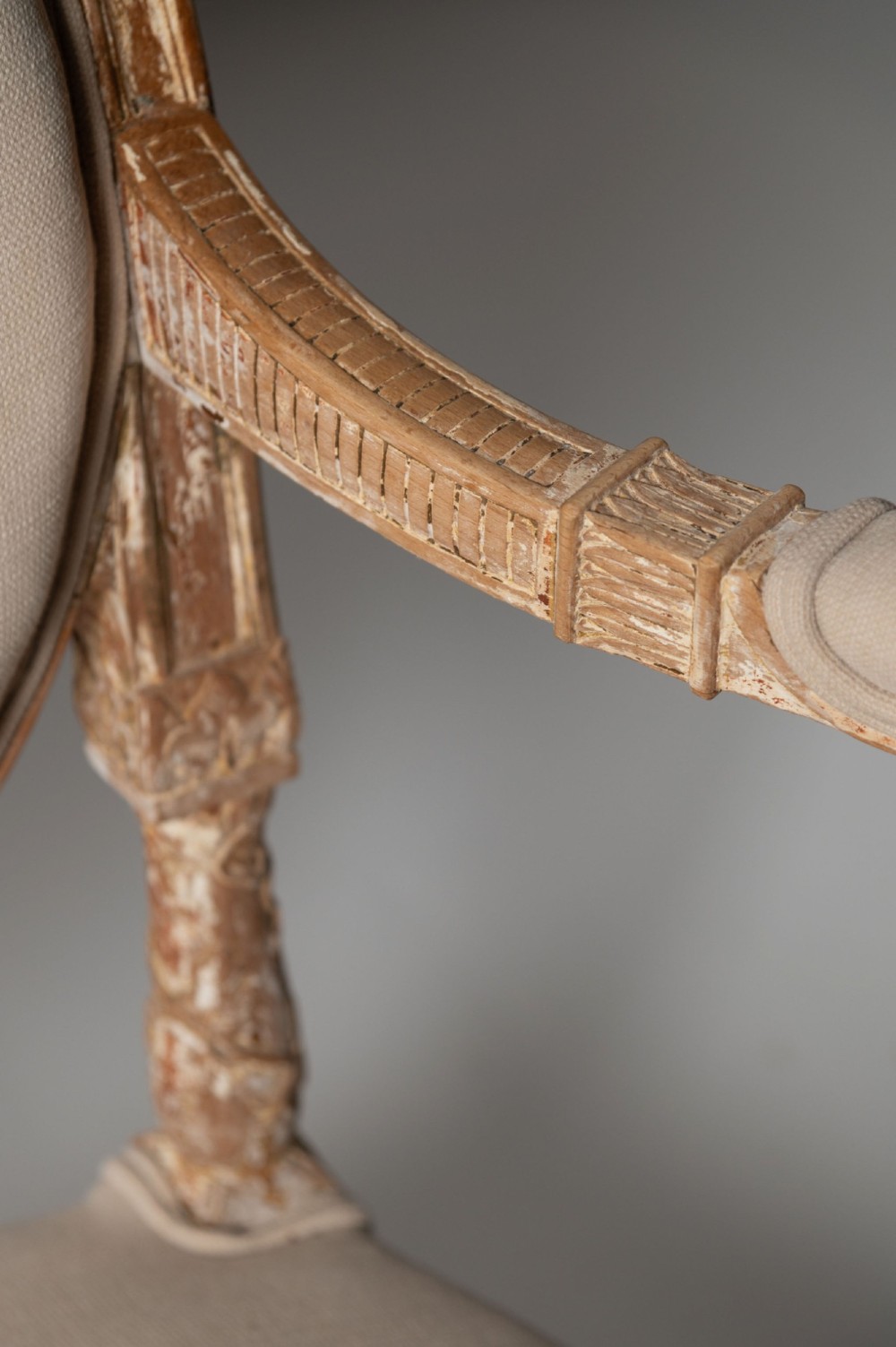 An antique Louis XVI style French settee featuring a distressed gilded wooden frame, oval medallion backrest, and cream linen upholstery. View VII