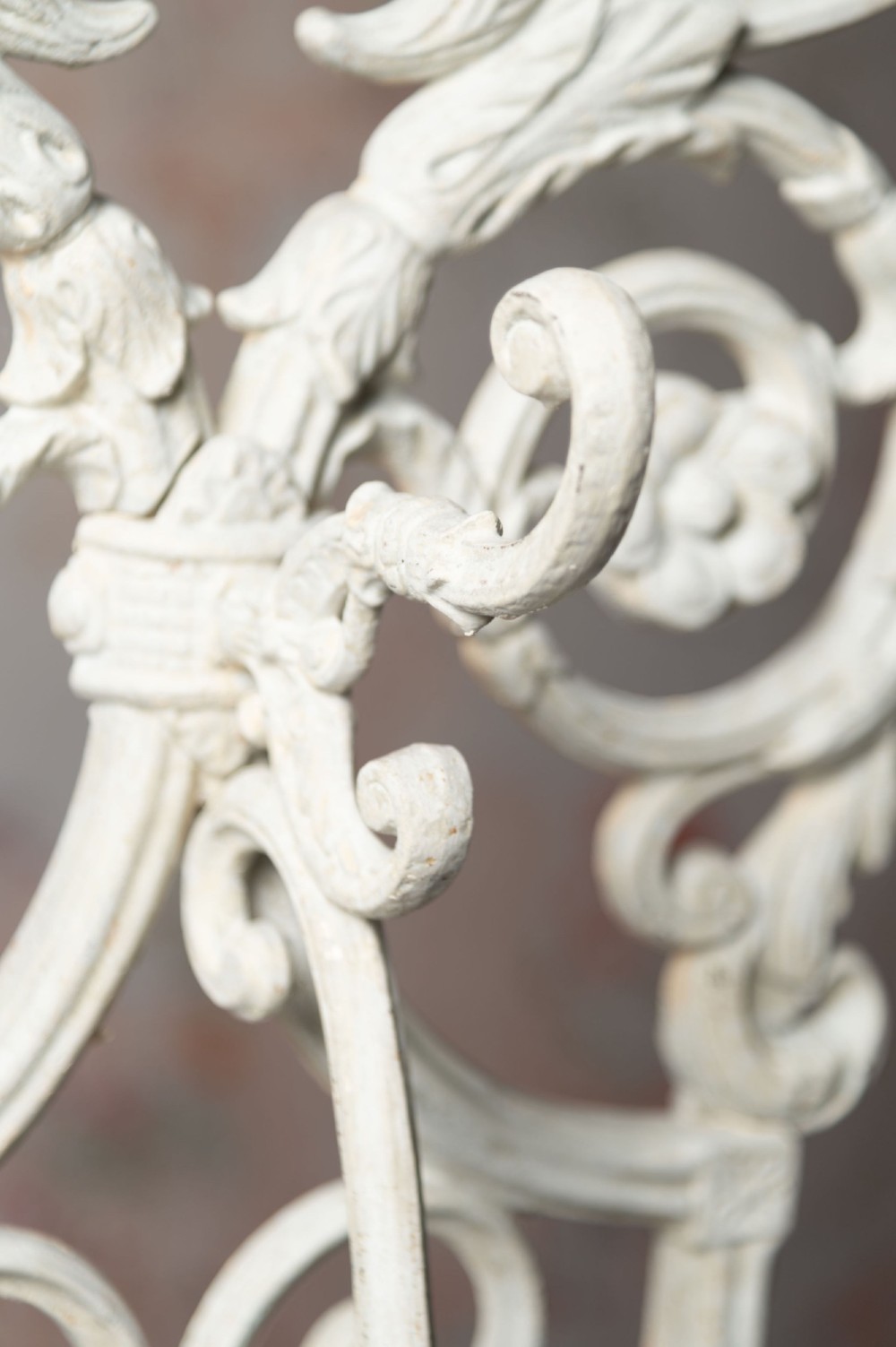 An antique white painted cast iron hall stand featuring intricate scrollwork, integrated coat hooks, a small central mirror, and a base drip tray. View V