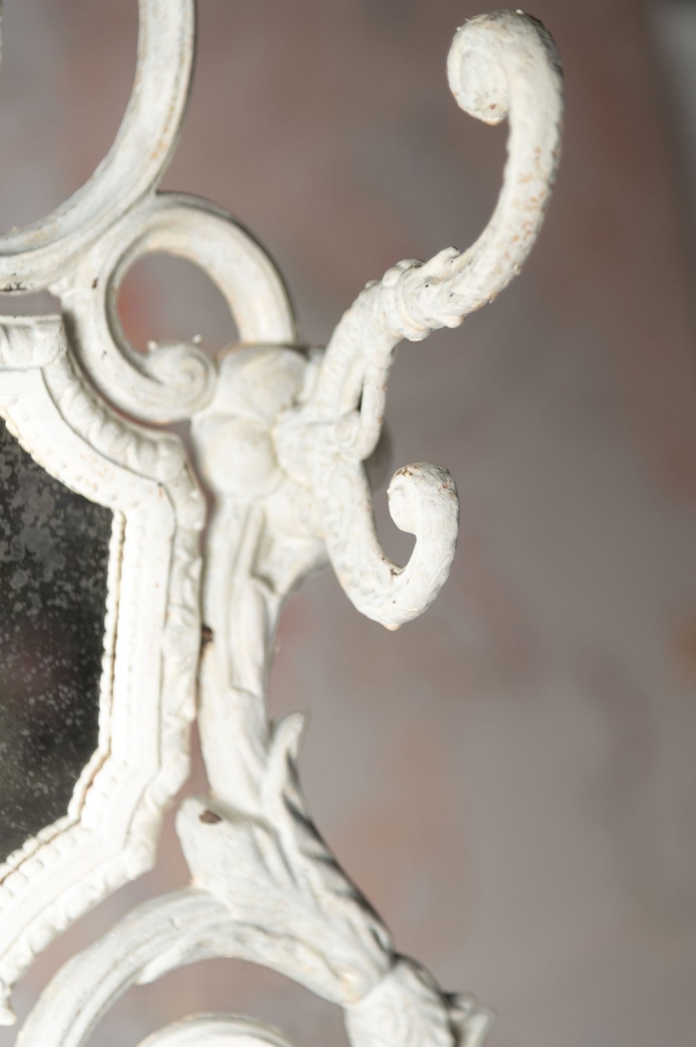 An antique white painted cast iron hall stand featuring intricate scrollwork, integrated coat hooks, a small central mirror, and a base drip tray. View VI