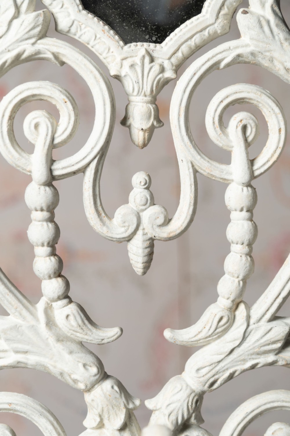 An antique white painted cast iron hall stand featuring intricate scrollwork, integrated coat hooks, a small central mirror, and a base drip tray. View VII