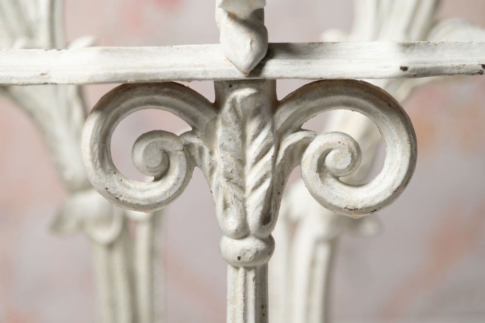 An antique white painted cast iron hall stand featuring intricate scrollwork, integrated coat hooks, a small central mirror, and a base drip tray. View IX