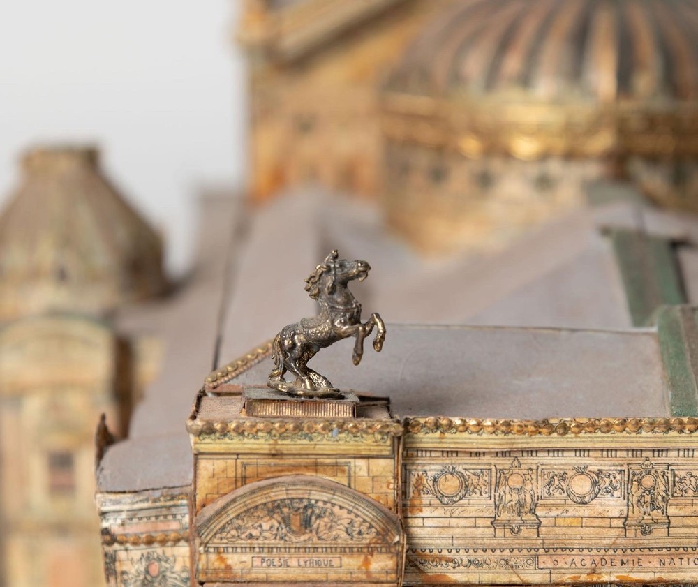 A detailed scale paper model of the Paris Opera House featuring a central dome, classical arcade facade, and miniature roof statuary mounted on a textured gravel base. View III
