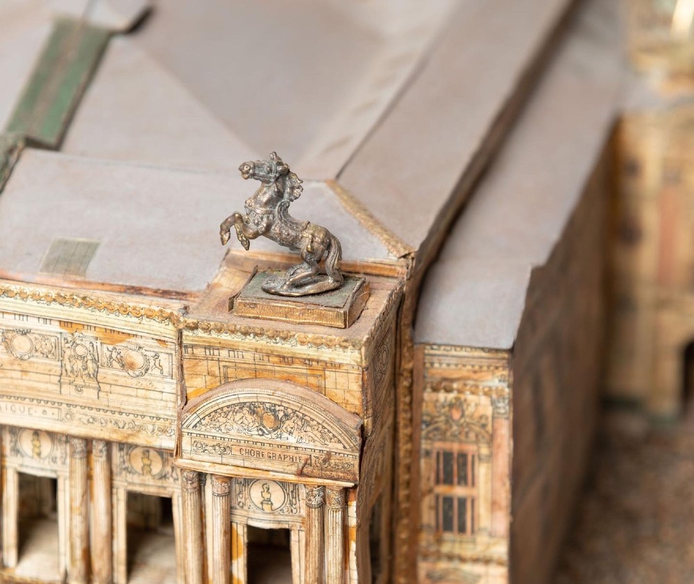 A detailed scale paper model of the Paris Opera House featuring a central dome, classical arcade facade, and miniature roof statuary mounted on a textured gravel base. View IV