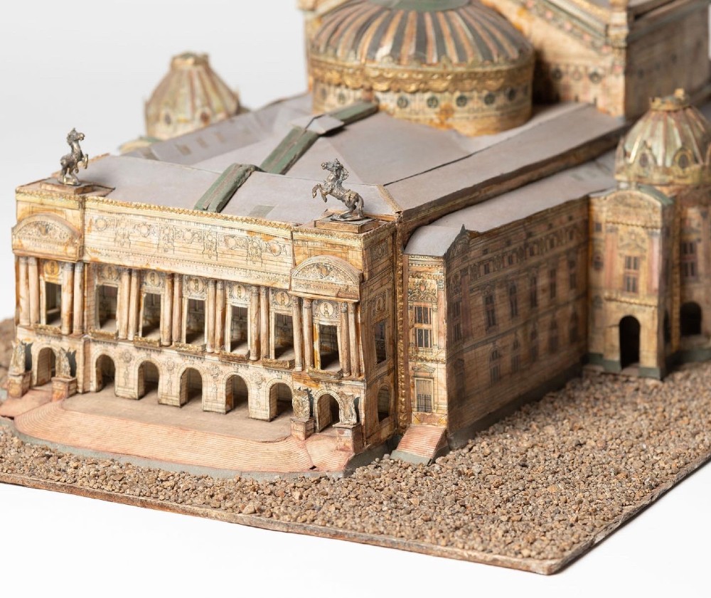 A detailed scale paper model of the Paris Opera House featuring a central dome, classical arcade facade, and miniature roof statuary mounted on a textured gravel base. View V