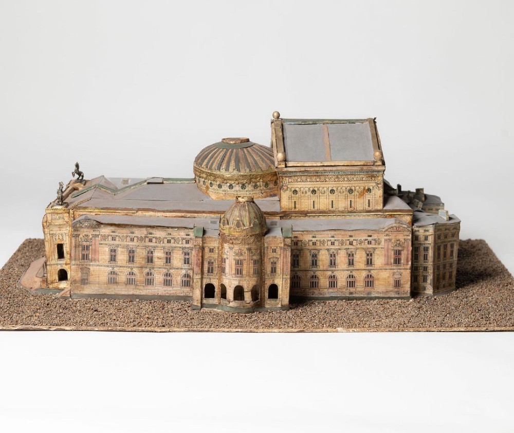 A detailed scale paper model of the Paris Opera House featuring a central dome, classical arcade facade, and miniature roof statuary mounted on a textured gravel base. View X