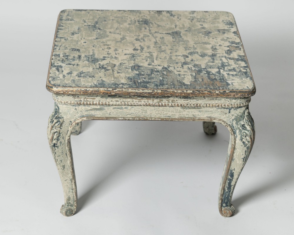 A square antique French side table featuring weathered grey and blue paint, carved cabriole legs, and bead moulding along the apron.