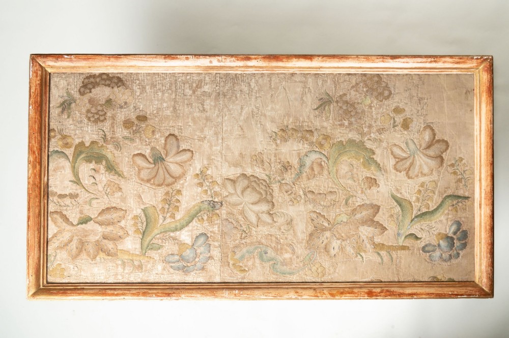 A low rectangular Italian giltwood coffee table featuring carved baroque supports, a scroll stretcher, and an inset floral textile top with a gilded frame. View II