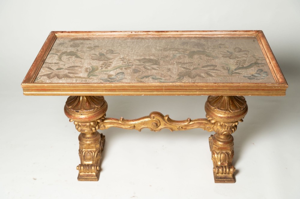 A low rectangular Italian giltwood coffee table featuring carved baroque supports, a scroll stretcher, and an inset floral textile top with a gilded frame. View VIII