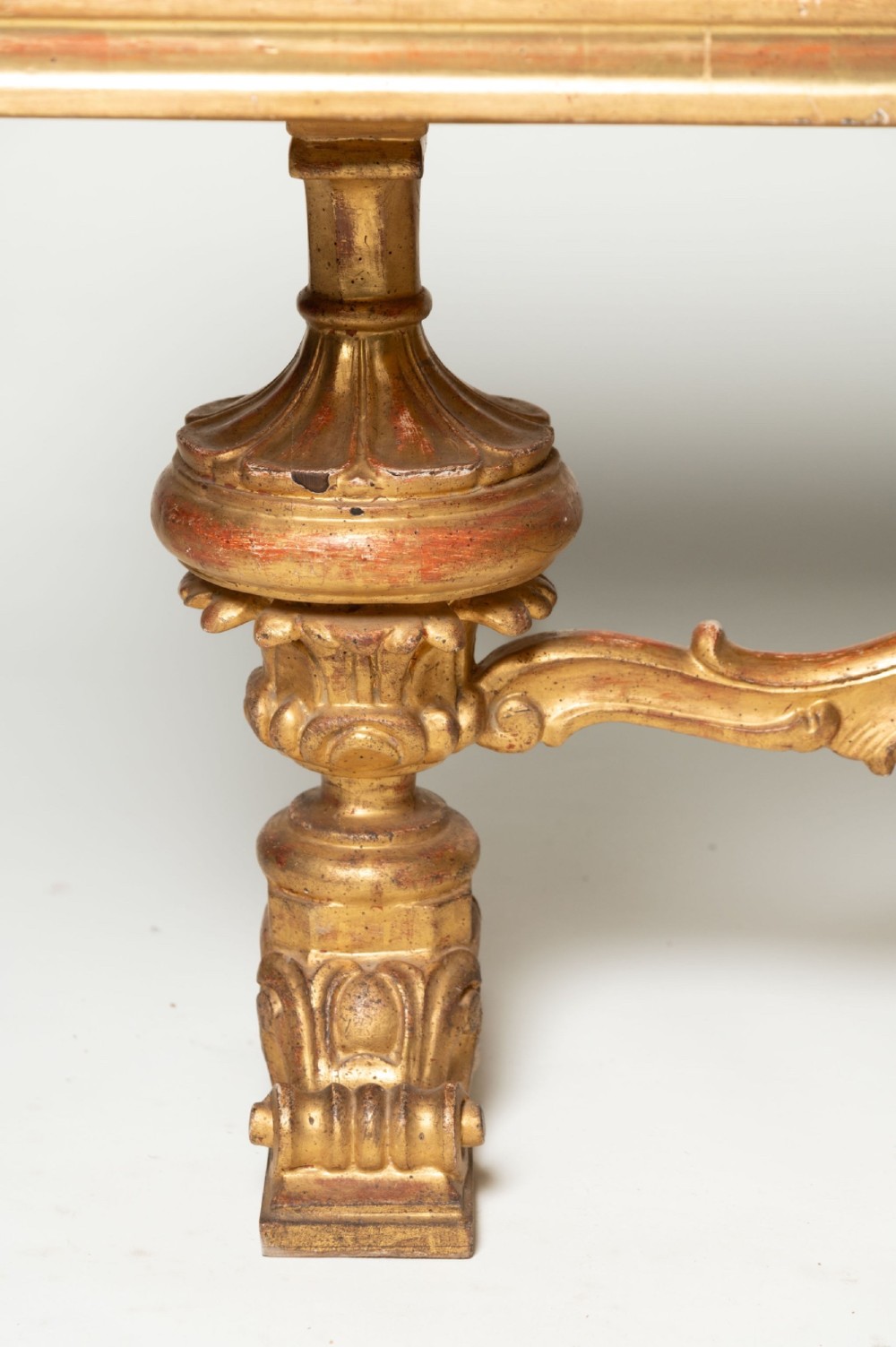 A low rectangular Italian giltwood coffee table featuring carved baroque supports, a scroll stretcher, and an inset floral textile top with a gilded frame. View IX