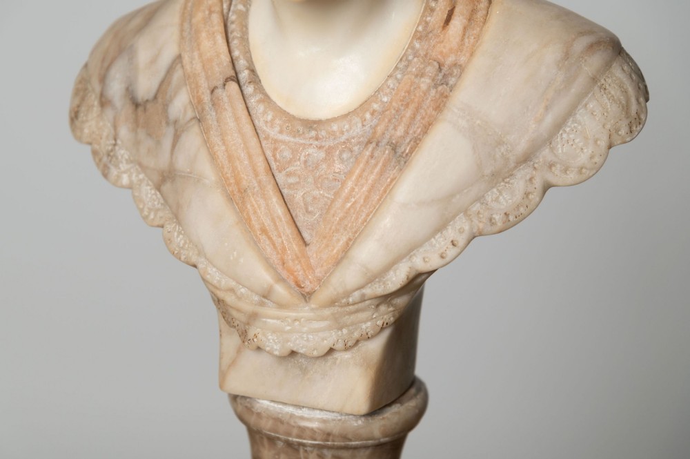 A carved cream alabaster bust depicting a female figure with stylized hair atop a polished turned stone socle. View III