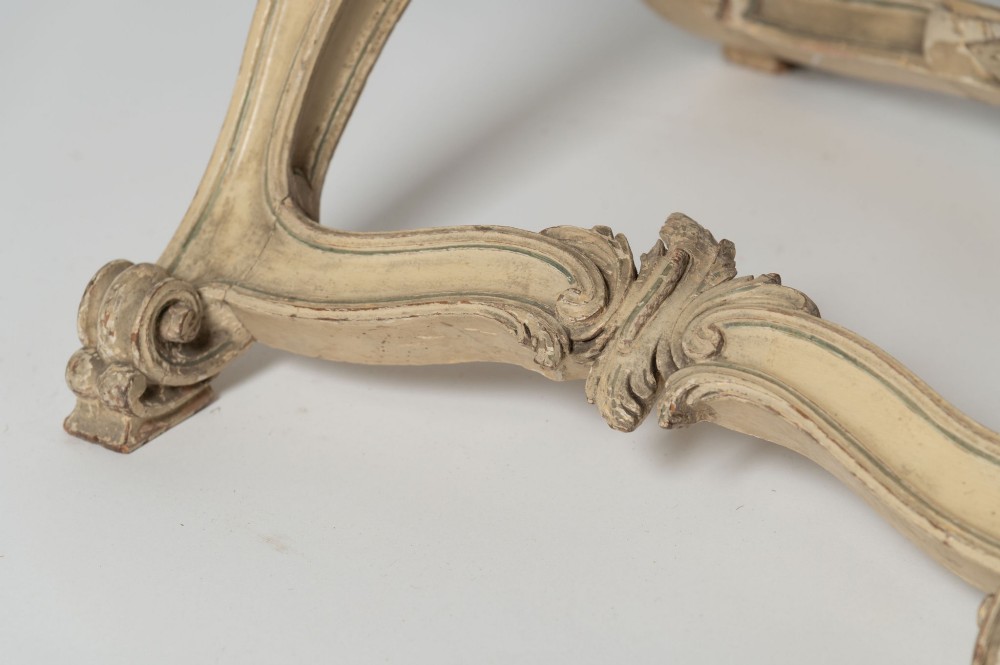 An antique French X-frame stool featuring a painted cream carved wooden base with rosette detailing and a neutral linen upholstered cushion. View IV