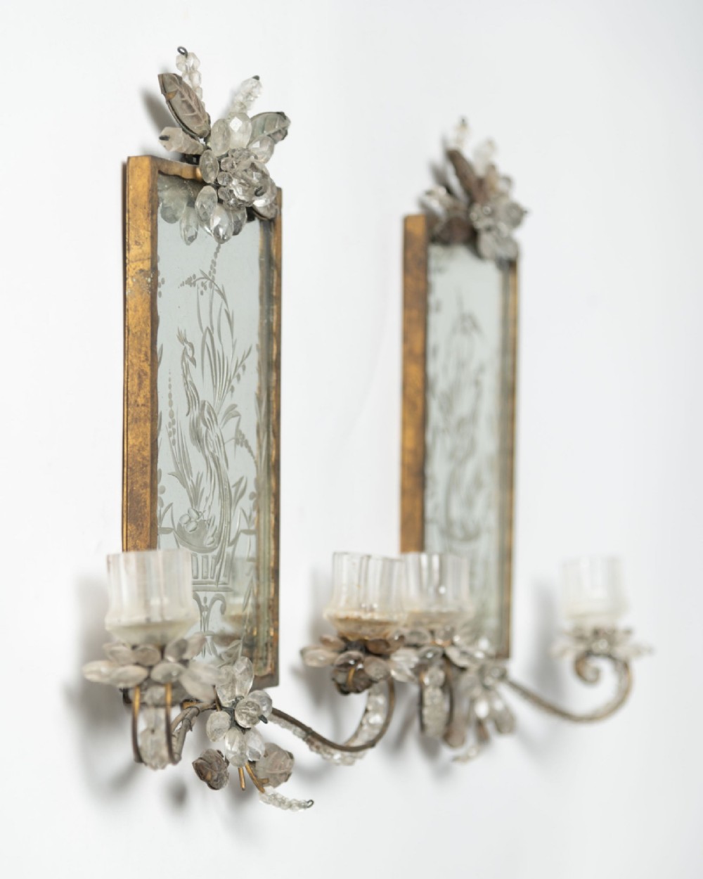 A pair of French gilt metal wall sconces featuring verre eglomise panels depicting birds, with floral crystal cresting and two scroll arms. View II
