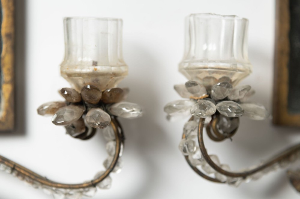 A pair of French gilt metal wall sconces featuring verre eglomise panels depicting birds, with floral crystal cresting and two scroll arms. View IV