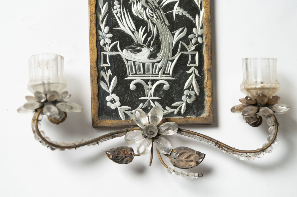 A pair of French gilt metal wall sconces featuring verre eglomise panels depicting birds, with floral crystal cresting and two scroll arms. View VII
