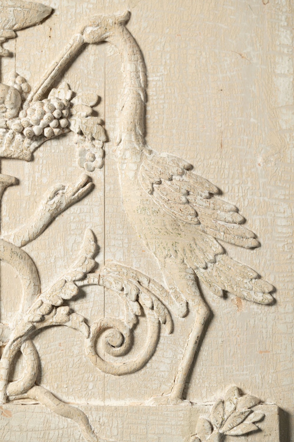 A rectangular off-white painted wood panel featuring an intricate raised relief carving of heraldic cranes, a fruit-filled urn, caduceus serpents, and laurel swags within a moulded frame. View III