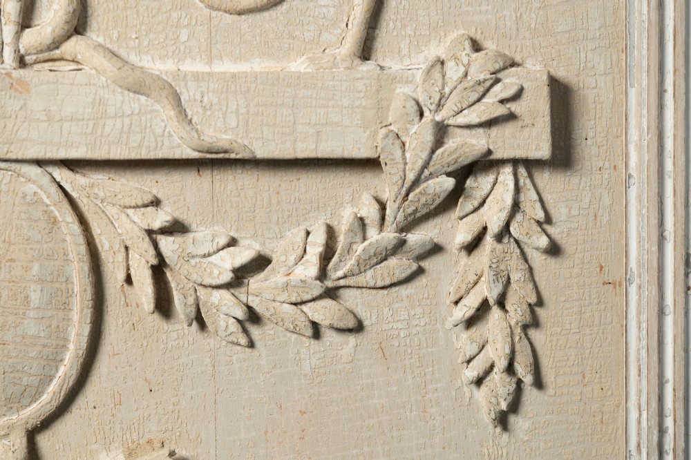 A rectangular off-white painted wood panel featuring an intricate raised relief carving of heraldic cranes, a fruit-filled urn, caduceus serpents, and laurel swags within a moulded frame. View VI