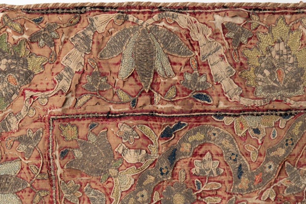 A rectangular 18th-century hand-embroidered textile featuring a central diamond medallion with floral arabesques and border patterns in shades of muted pink, sage green, and cream. View VI