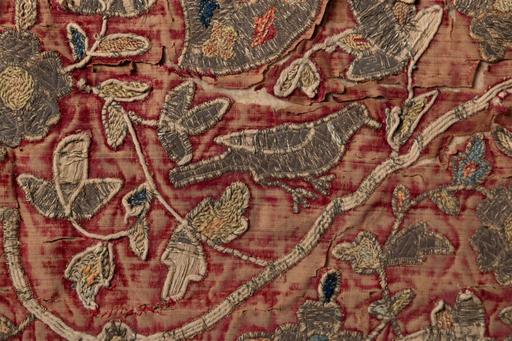 A rectangular 18th-century hand-embroidered textile featuring a central diamond medallion with floral arabesques and border patterns in shades of muted pink, sage green, and cream. View VII