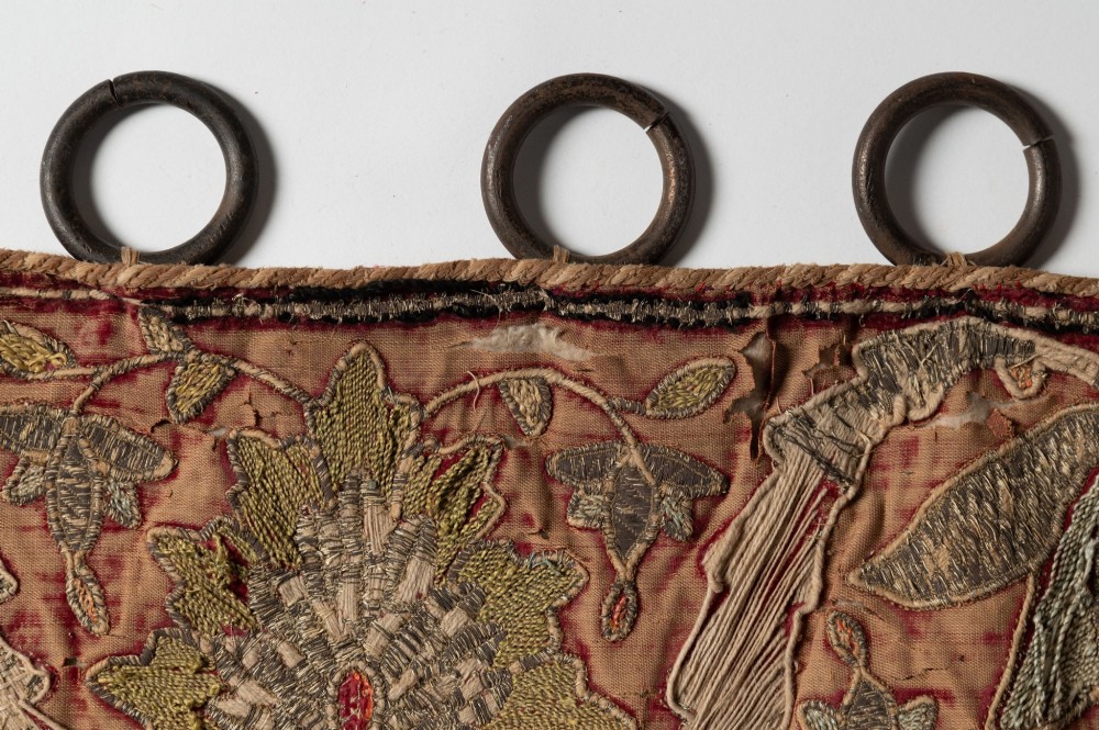 A rectangular 18th-century hand-embroidered textile featuring a central diamond medallion with floral arabesques and border patterns in shades of muted pink, sage green, and cream. View IX