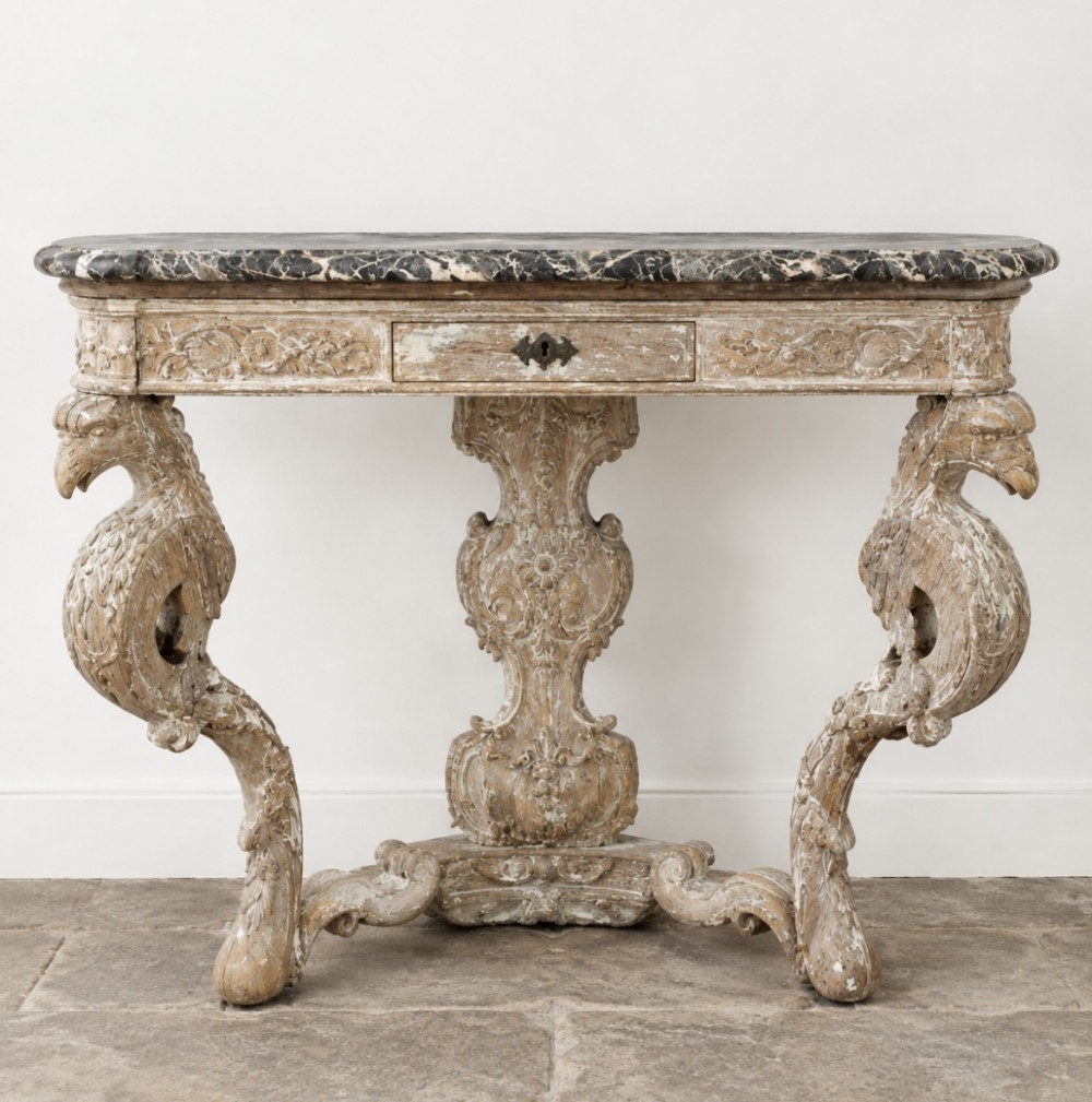 An 18th-century carved wooden console table featuring eagle-shaped leg supports, a central pedestal, a single small drawer, and a dark veined marble top.