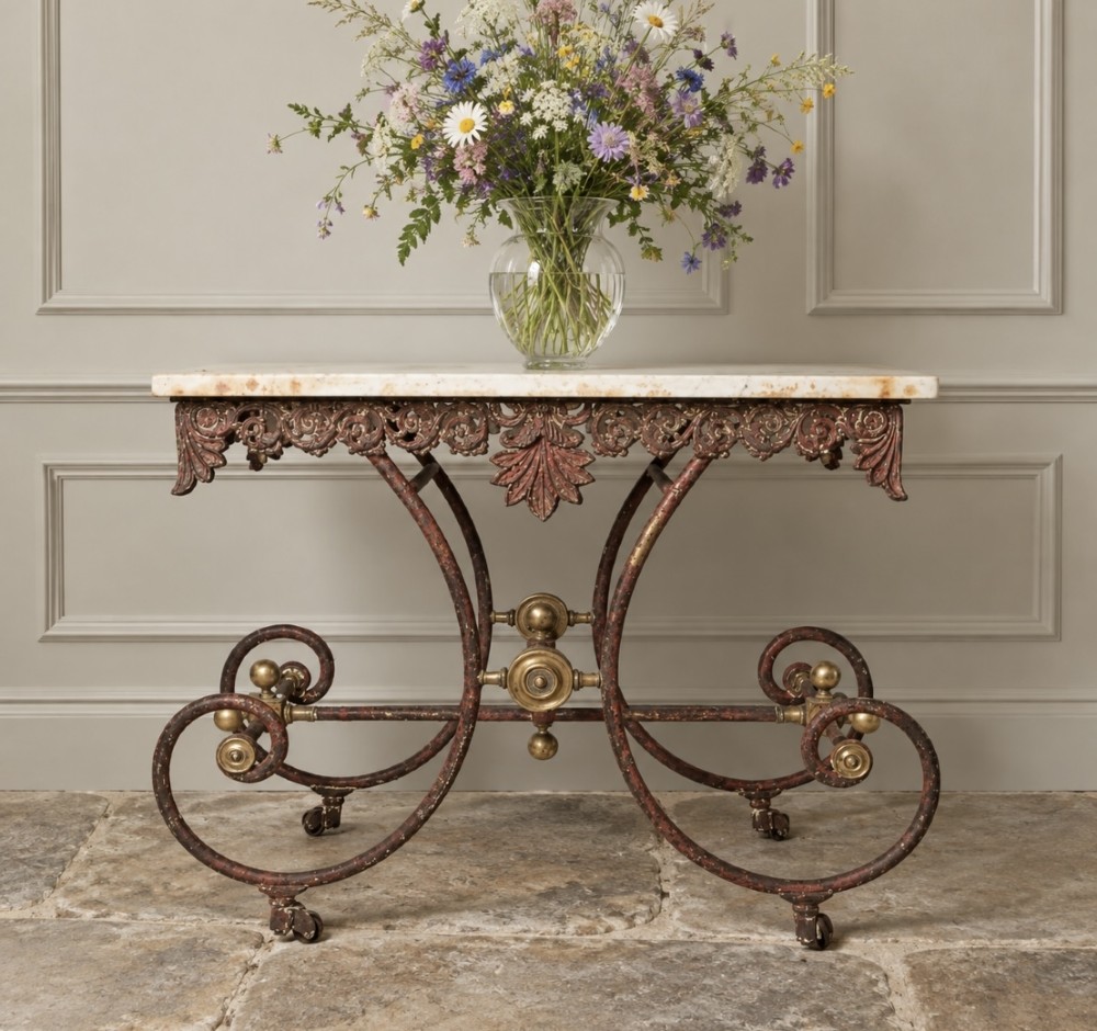 A 19th-century French butcher table featuring a thick white marble top above an intricate scrollwork wrought iron base painted in red with brass decorative mounts.