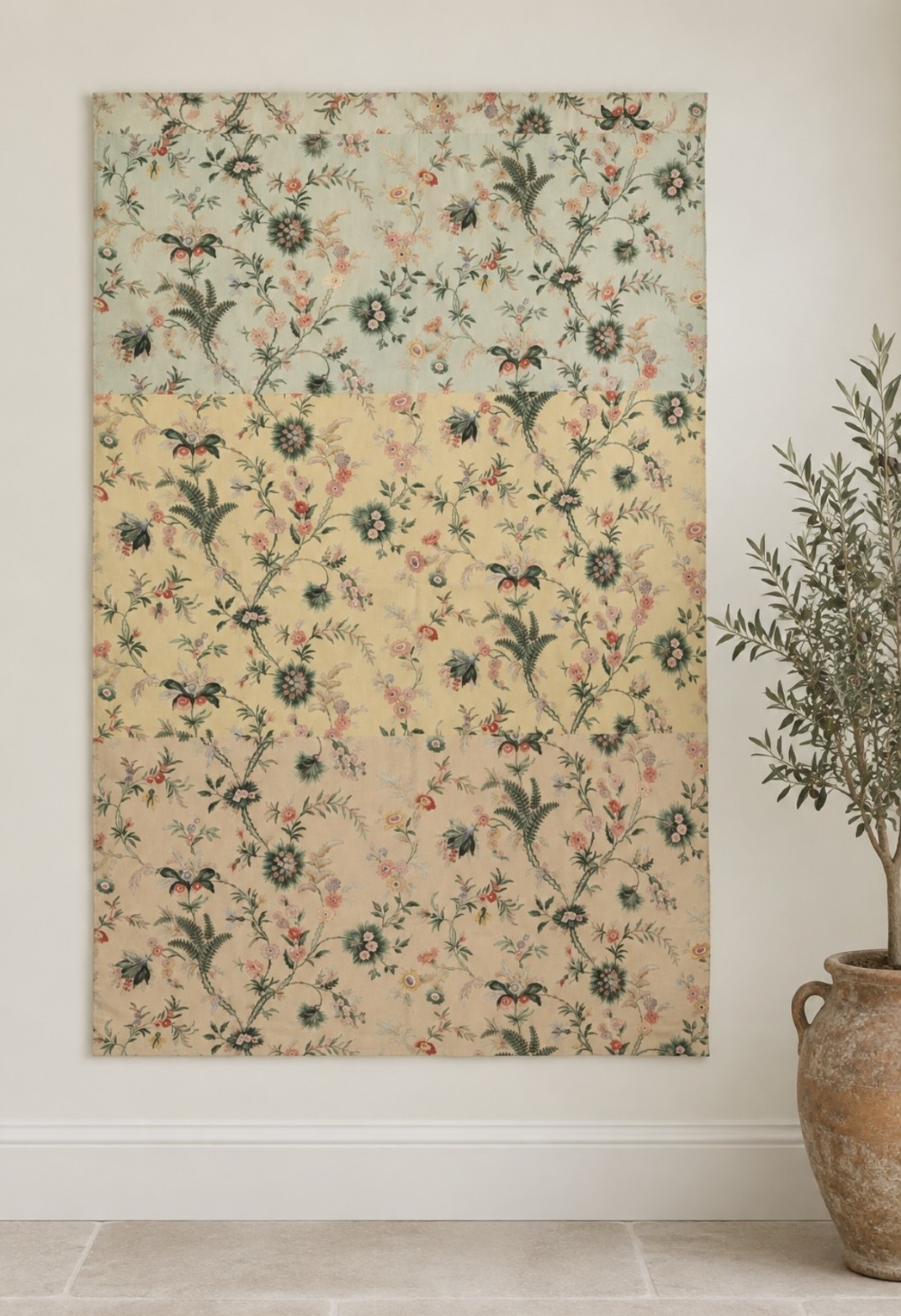 A large rectangular fabric wall panel displaying three distinct horizontal bands in mint green, yellow, and blush peach with trailing botanical fern and floral foliage motifs.