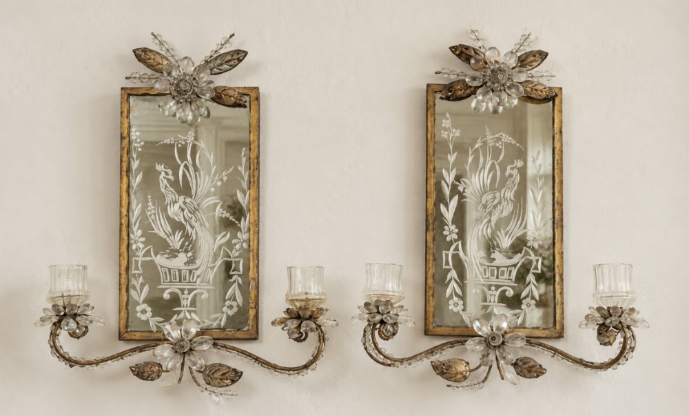 A pair of gilt metal and etched glass wall sconces featuring rectangular mirrored backplates with bird motifs and crystal flower embellishments.