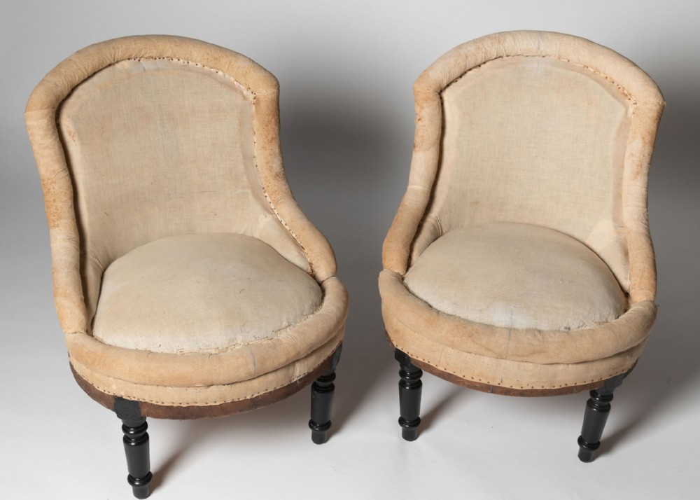 A pair of 19th-century French crapaud armchairs upholstered in beige calico lining with dark ebonised turned wooden front legs.