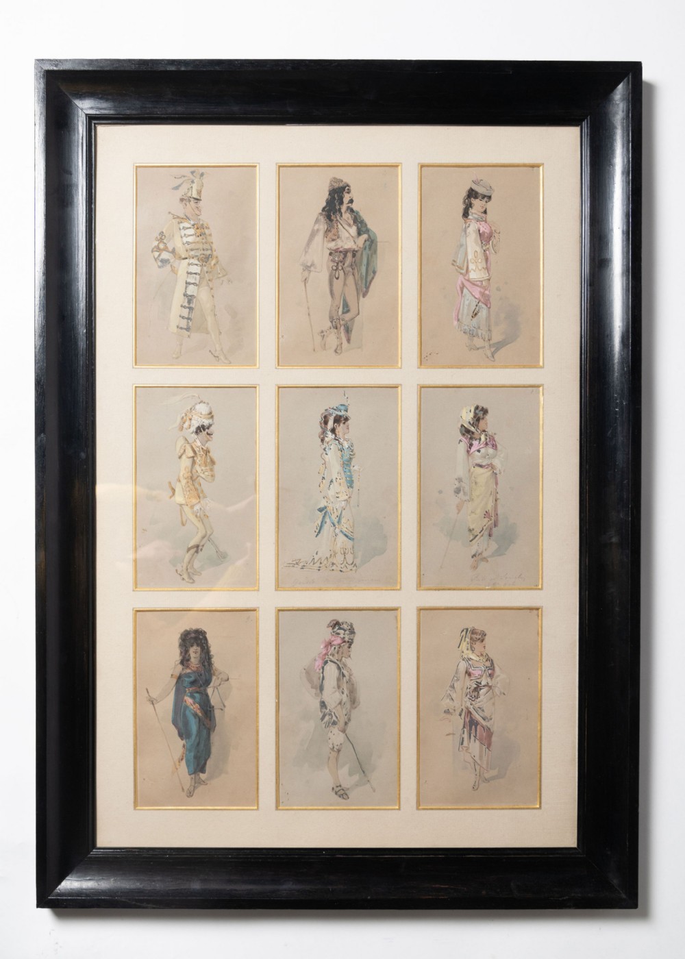 A large black-framed picture displaying nine individual watercolour costume studies of figures in historical attire arranged in a three-by-three grid inside a cream mount.