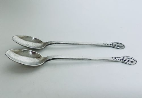 fig 1. A pair of Danish silver teaspoons with stylised floral finials on the upper handles and oval bowls resting on a plain surface.
