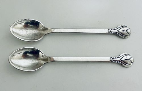fig 2. A pair of Danish silver teaspoons with stylised floral finials on the upper handles and oval bowls resting on a plain surface.