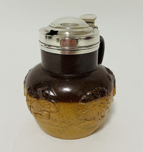fig 1. A Victorian two-tone brown stoneware mustard pot featuring relief-moulded rural scenes, a side handle, and a polished silver hinged lid.