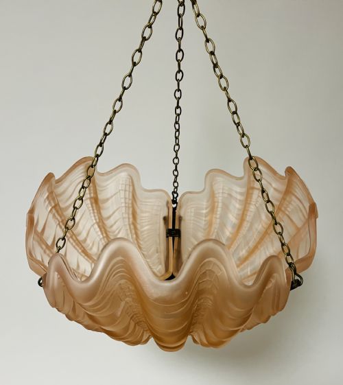 fig 1. An Art Deco pink frosted glass clam shell ceiling pendant light suspended by three brass hanging chains.
