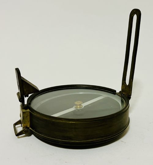fig 2. An antique brass surveying compass featuring folding sight vanes, a central needle, and a glass-covered dial.