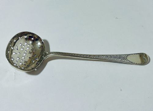 fig 1. An antique Georgian silver sugar sifter spoon featuring a pierced bowl and an engraved handle.